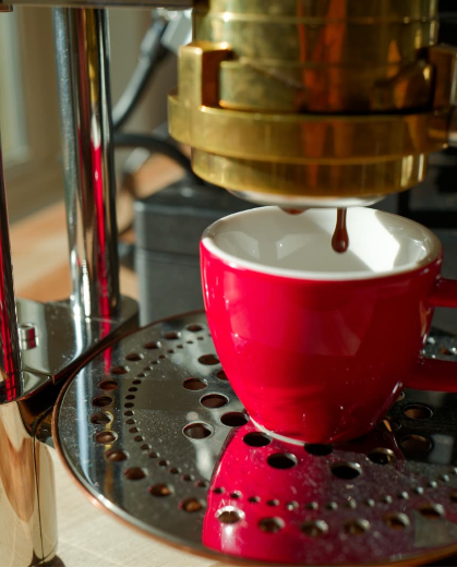Red cup being filled with coffee from a espresso machine.